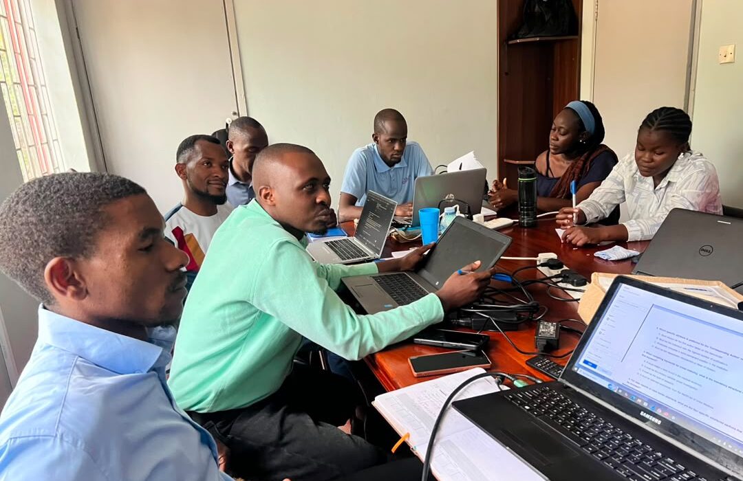 NexusCRI participants working together around a table with laptops, notes and research materials.