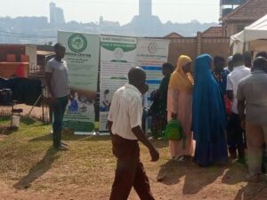 People gathered outdoors beside Nexus Centre and Islamic University in Uganda banners during an engagement activity.